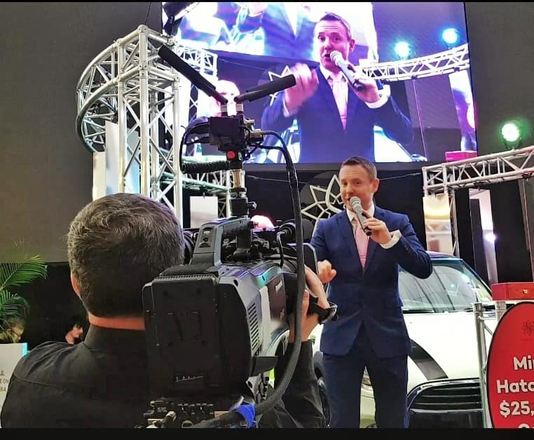 Tony Morrison hosting a corporate event with live broadcast screen